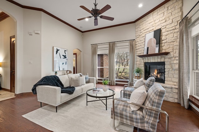 living area featuring a fireplace, arched walkways, wood finished floors, and ornamental molding