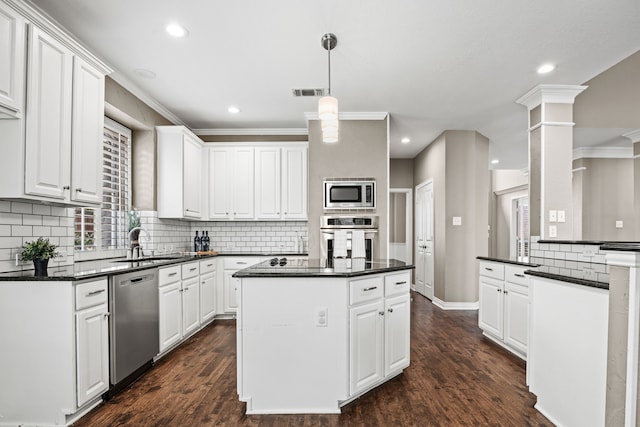 kitchen with dark countertops, appliances with stainless steel finishes, and white cabinets