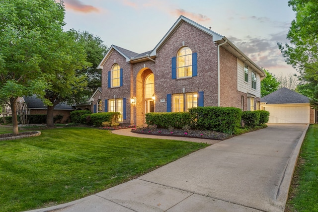 traditional-style home with an outbuilding, brick siding, a front yard, and a detached garage