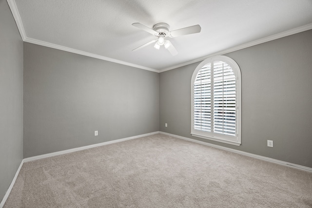 carpeted empty room with ceiling fan, ornamental molding, and baseboards