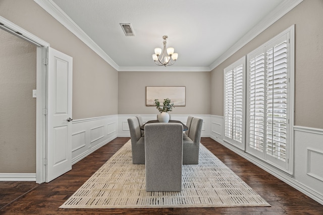 dining area featuring a wainscoted wall, visible vents, ornamental molding, dark wood-style floors, and an inviting chandelier