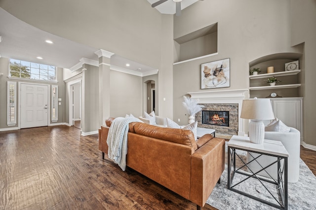 living room featuring built in shelves, dark wood-style flooring, baseboards, and a high ceiling