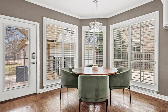 dining space with ornamental molding, an inviting chandelier, and wood finished floors