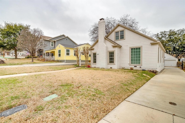 view of front facade featuring crawl space, a chimney, a front yard, and a gate