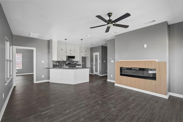 kitchen featuring visible vents, white cabinets, dark countertops, stainless steel microwave, and hanging light fixtures