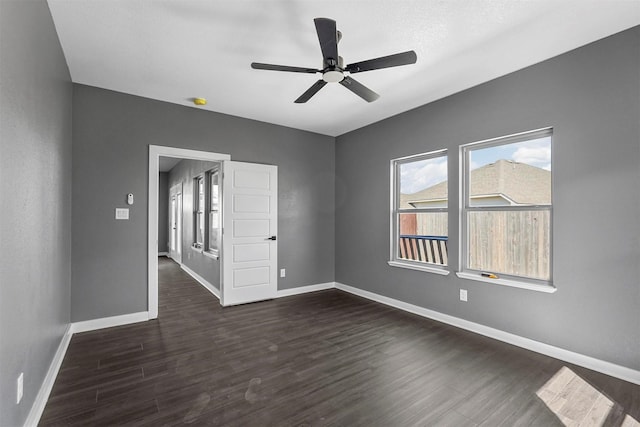 spare room with dark wood finished floors, baseboards, and ceiling fan