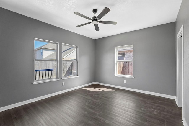 spare room with dark wood-style floors, baseboards, and a ceiling fan