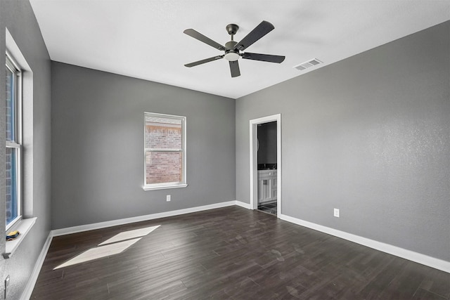 unfurnished room with dark wood-style floors, visible vents, ceiling fan, and baseboards