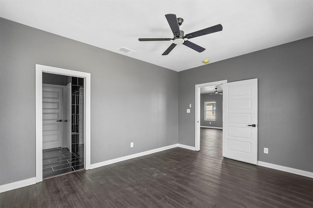 unfurnished bedroom featuring baseboards, visible vents, ceiling fan, and dark wood-style flooring