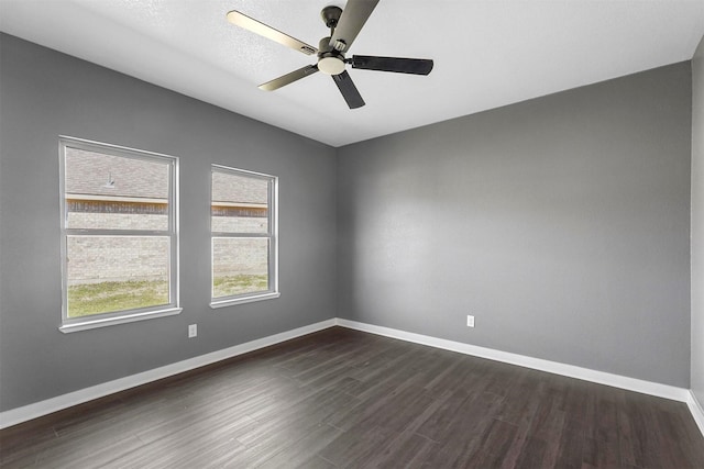 empty room with dark wood finished floors, baseboards, and ceiling fan