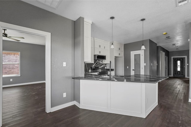 kitchen with visible vents, white cabinets, decorative light fixtures, a peninsula, and stainless steel appliances