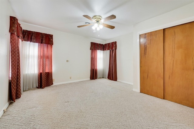 unfurnished bedroom with light carpet, a closet, baseboards, and a ceiling fan