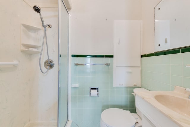 full bath featuring tile walls, toilet, a stall shower, wainscoting, and vanity