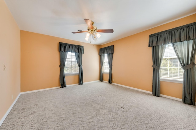 carpeted spare room with a ceiling fan and baseboards