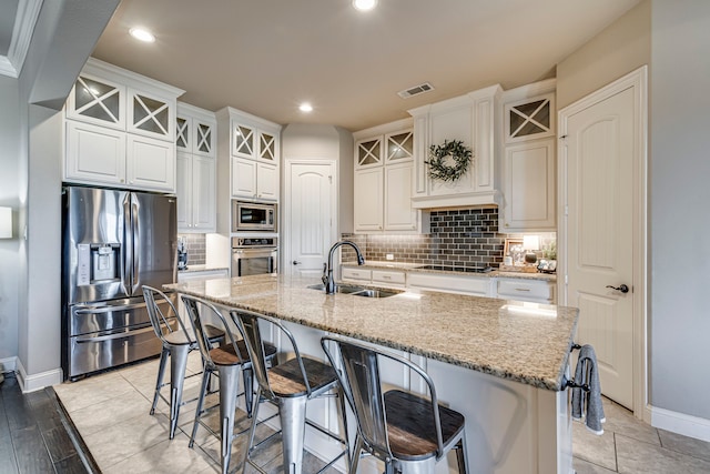 kitchen featuring a sink, visible vents, white cabinetry, appliances with stainless steel finishes, and an island with sink