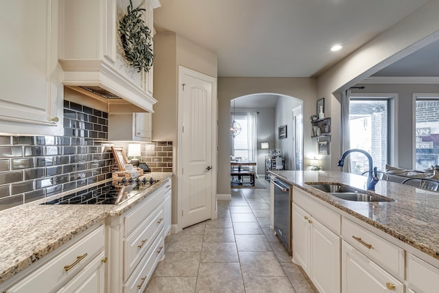 kitchen with white cabinetry, light stone counters, and a sink