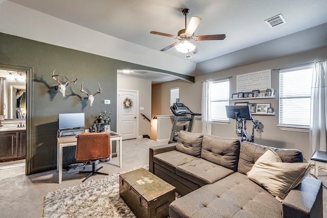 living room featuring light carpet, baseboards, visible vents, arched walkways, and a ceiling fan