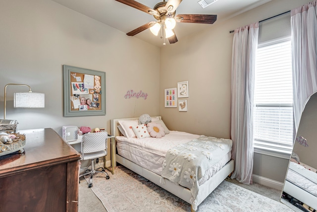 bedroom featuring light carpet, ceiling fan, multiple windows, and baseboards