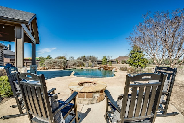 pool with an outdoor fire pit, a patio area, and fence