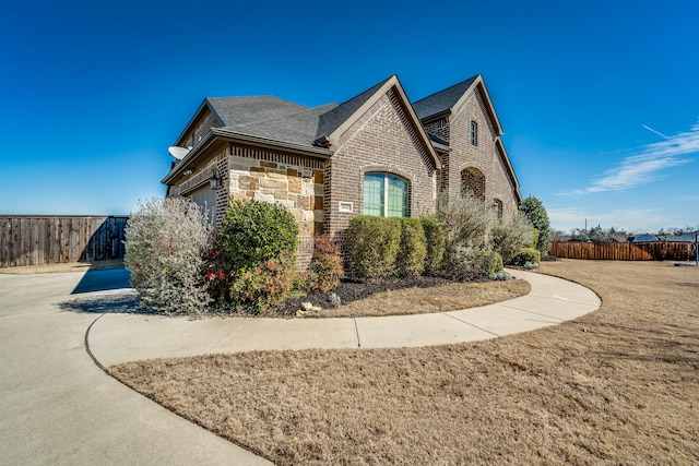 view of side of home with brick siding, a lawn, fence, a garage, and stone siding