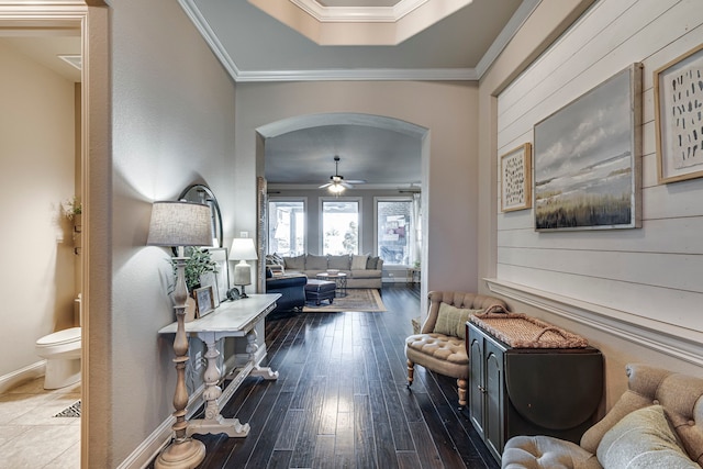 interior space with baseboards, arched walkways, wood finished floors, and ornamental molding