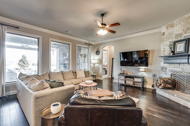 living room with crown molding, arched walkways, visible vents, and plenty of natural light