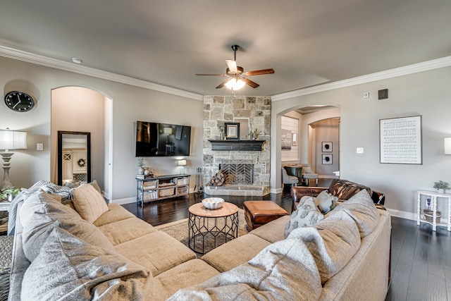 living room featuring arched walkways, a stone fireplace, dark wood-style floors, and ornamental molding