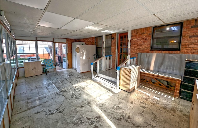 interior space featuring a drop ceiling and brick wall