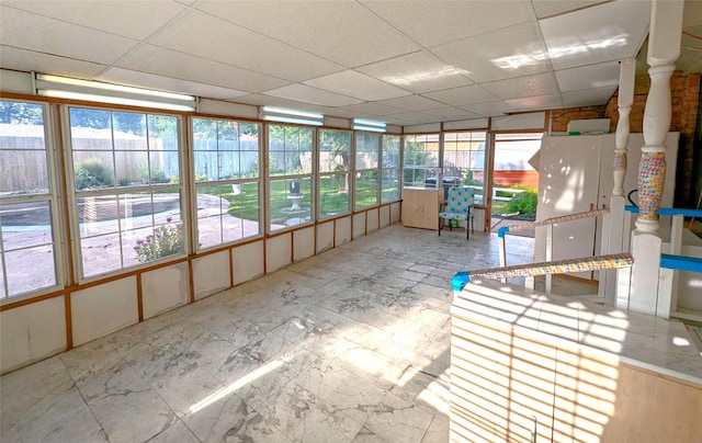 unfurnished sunroom featuring a drop ceiling