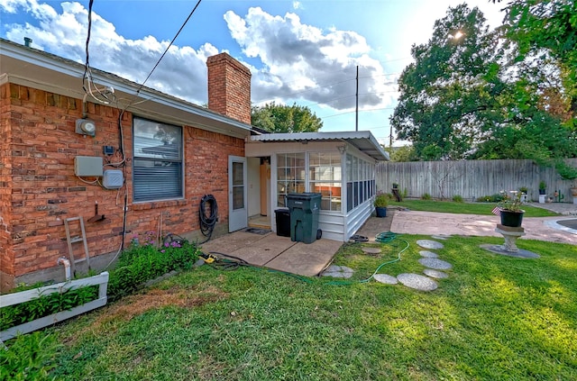 back of house featuring a patio, a chimney, fence, a yard, and brick siding