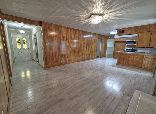 kitchen featuring light wood-style flooring, stainless steel appliances, light countertops, brown cabinetry, and crown molding