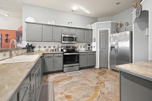 kitchen with visible vents, stainless steel appliances, light countertops, gray cabinetry, and a sink