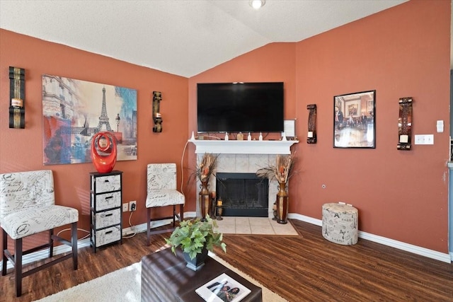 living room featuring lofted ceiling, a tiled fireplace, wood finished floors, and baseboards