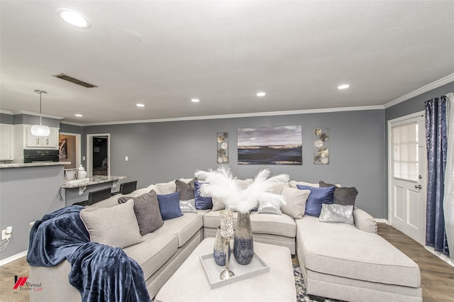 living area with baseboards, visible vents, ornamental molding, wood finished floors, and recessed lighting