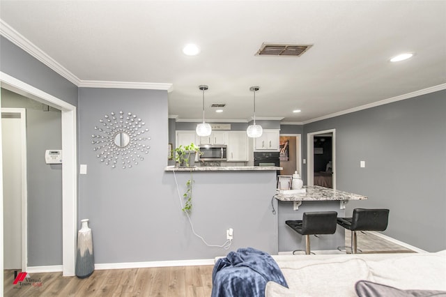 kitchen with visible vents, a kitchen breakfast bar, black oven, stainless steel microwave, and pendant lighting