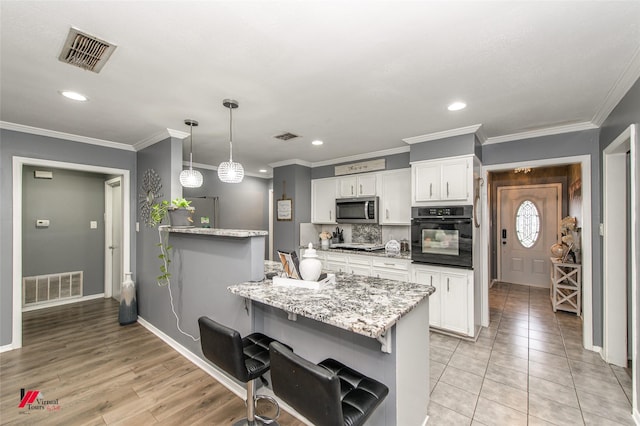 kitchen with white cabinetry, visible vents, pendant lighting, and stainless steel appliances