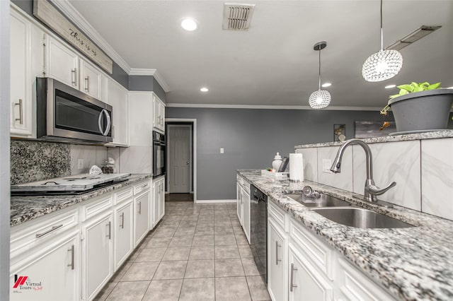 kitchen featuring light stone counters, a sink, white cabinets, black appliances, and decorative light fixtures