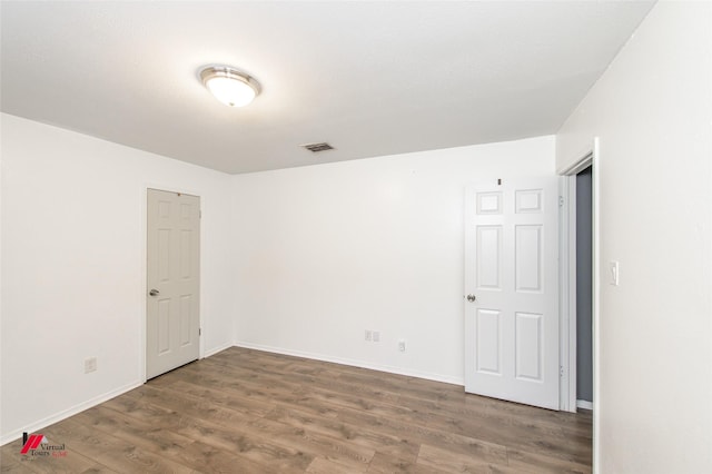 spare room with dark wood-style floors, visible vents, and baseboards