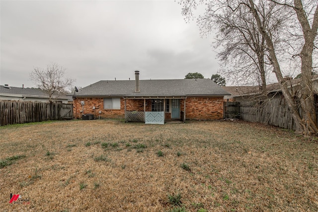 back of house featuring brick siding, a lawn, cooling unit, and a fenced backyard