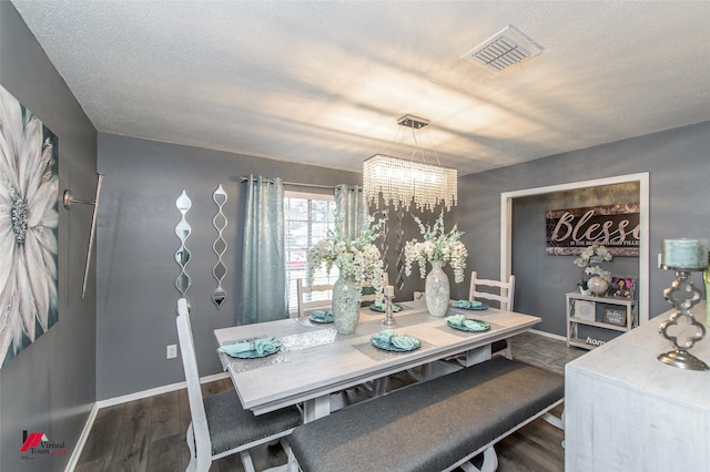 dining space with dark wood-type flooring, visible vents, baseboards, and an inviting chandelier