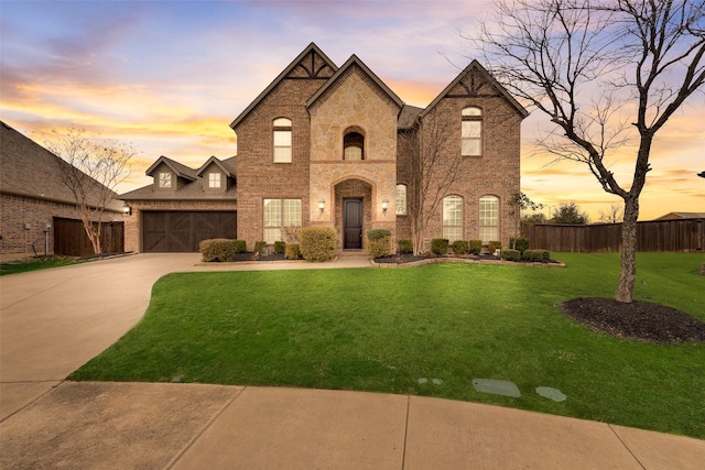 french provincial home with driveway, brick siding, a front lawn, and an attached garage