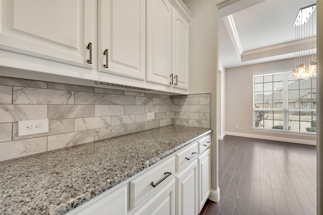 kitchen featuring a tray ceiling, white cabinetry, dark wood finished floors, and light stone countertops