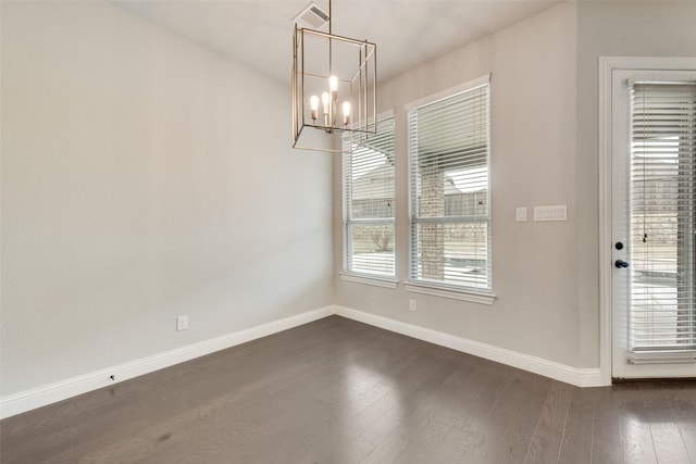 unfurnished dining area featuring a notable chandelier, dark wood finished floors, visible vents, and baseboards