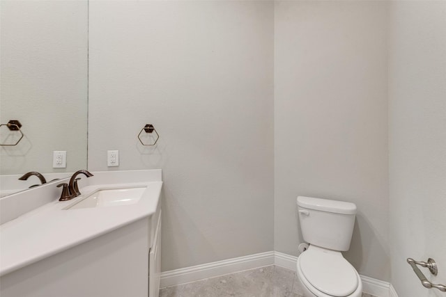 bathroom featuring toilet, vanity, and baseboards