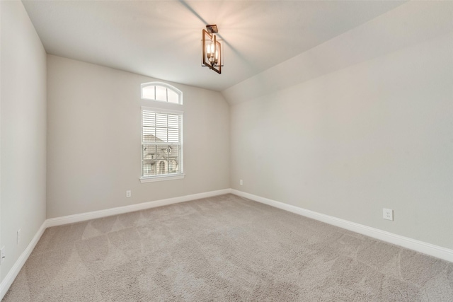 empty room with baseboards, vaulted ceiling, and carpet flooring