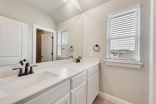 full bathroom with lofted ceiling, double vanity, a sink, and baseboards