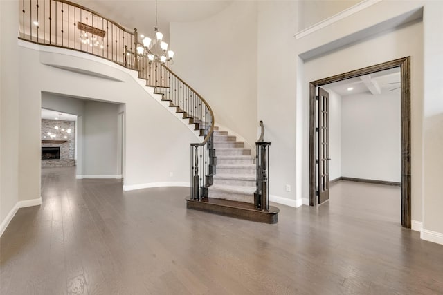 foyer entrance with dark wood-type flooring, stairway, a high ceiling, and baseboards