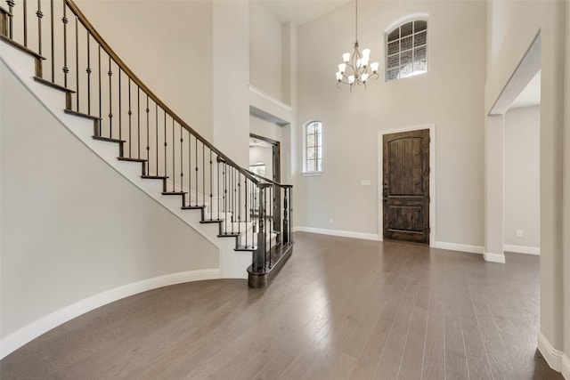 entrance foyer with stairs, baseboards, a chandelier, and wood finished floors