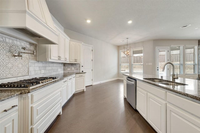 kitchen featuring stainless steel appliances, visible vents, white cabinets, a sink, and dark stone countertops