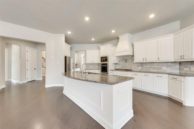 kitchen with stainless steel appliances, premium range hood, a sink, and white cabinets